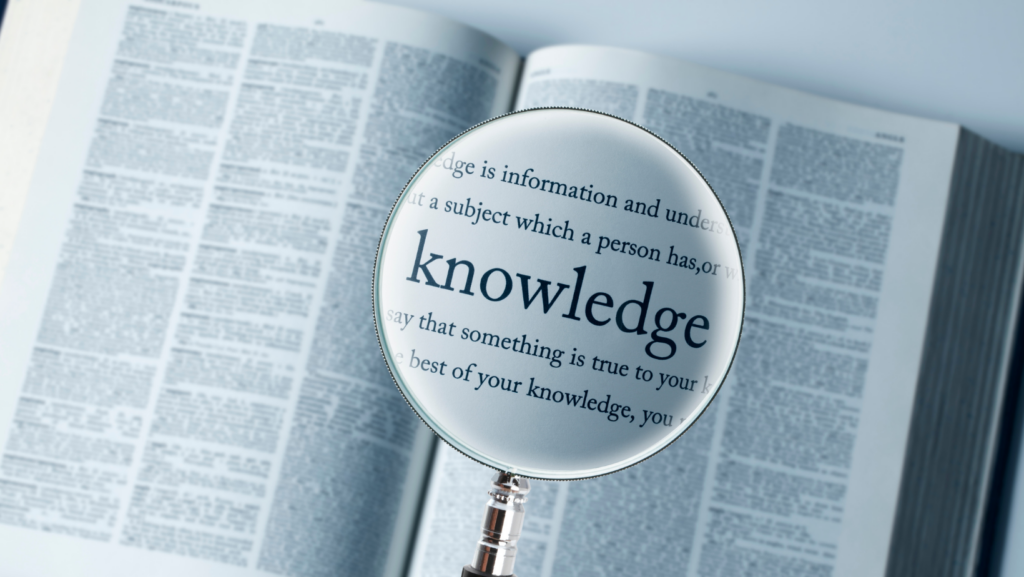 magnifying glass hovering over the word knowledge in a book