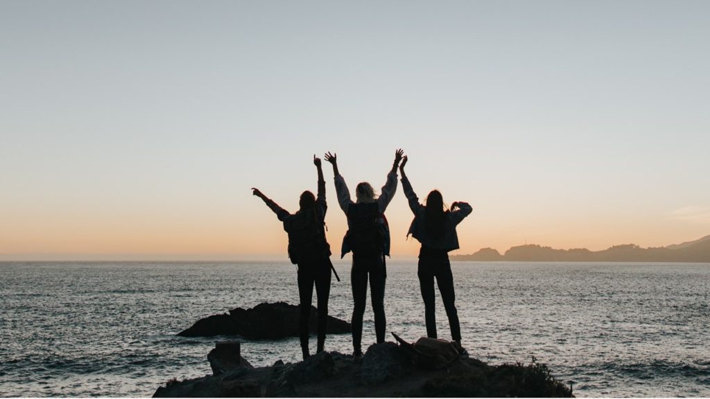 Women holding hands in front of the ocean