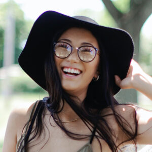 woman wearing glasses holding her hat